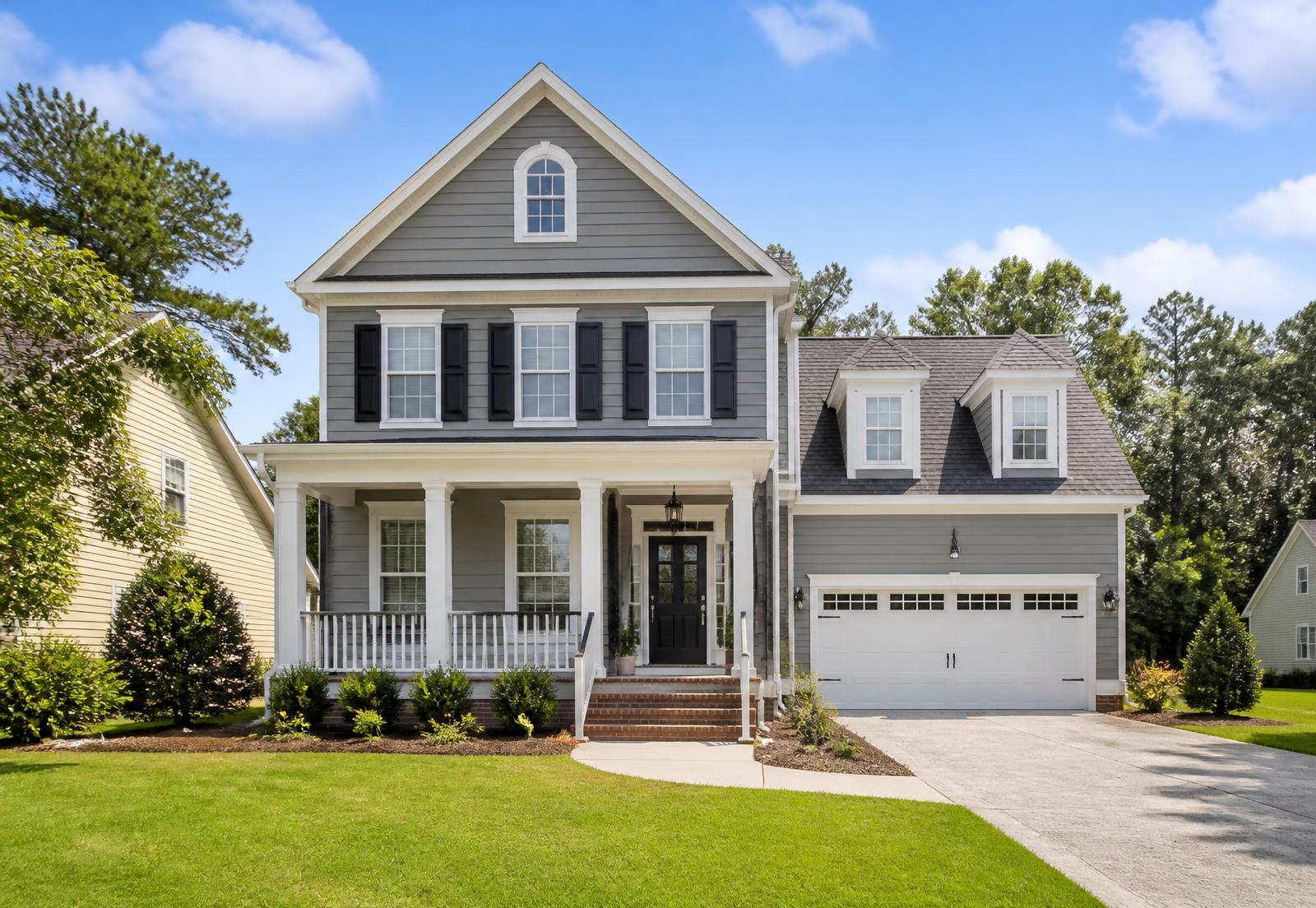 Gray two-story home with freshly painted white trim and black shutters